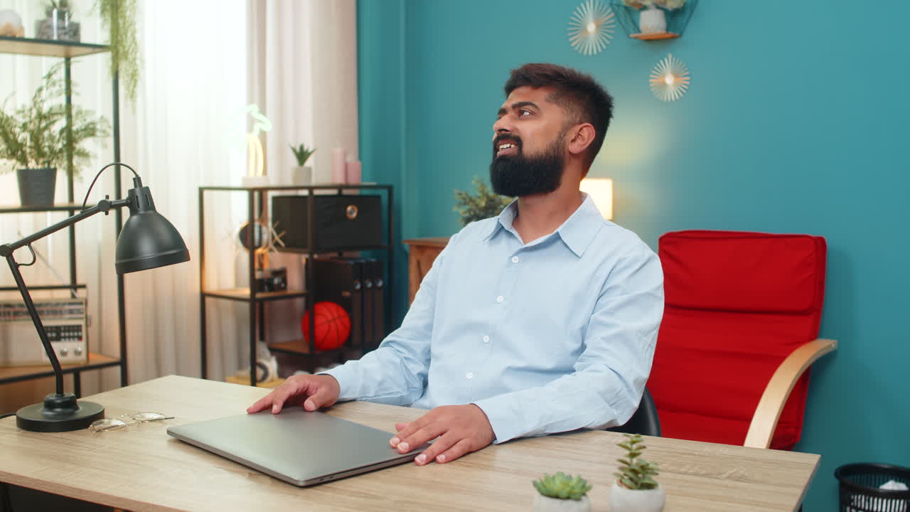 Indian man closes laptop satisfied job done relaxes hands behind head smiles enjoying project great