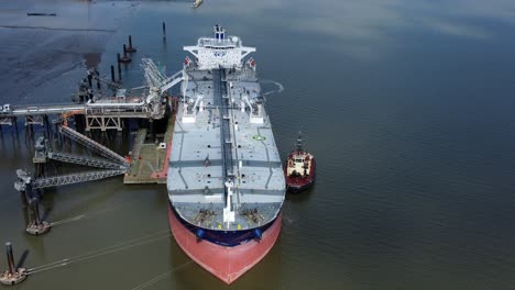 crude oil tanker ship loading at refinery harbour terminal aerial view pull away from bow tilt up