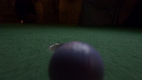 Ein-Lila-Minigolfball-Fällt-In-Das-Golfloch-Und-Springt-In-Der-Tasche-Auf-Einem-Kurs