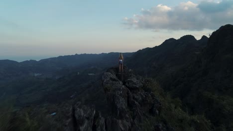 woman enjoys view from kandungaw peak during sunset, looking at valley, aerial