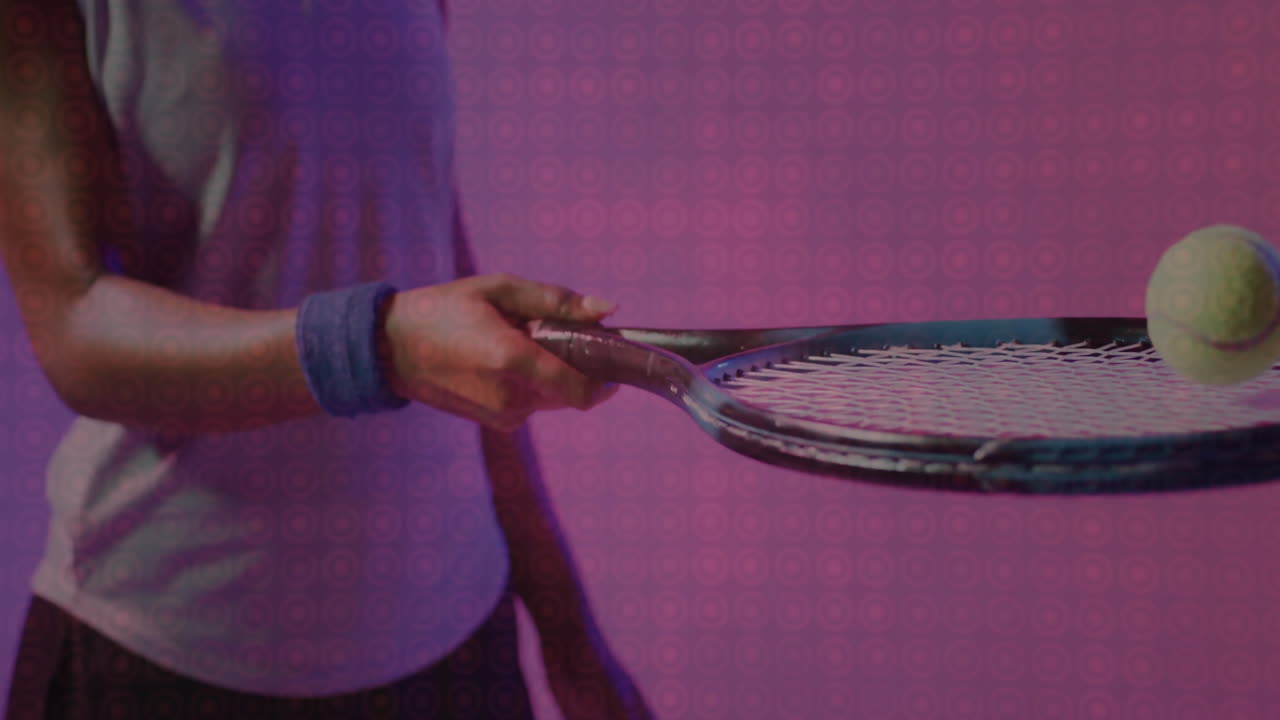 Woman holding tennis racket balancing tennis ball in studio, showing animated fitness data overlays