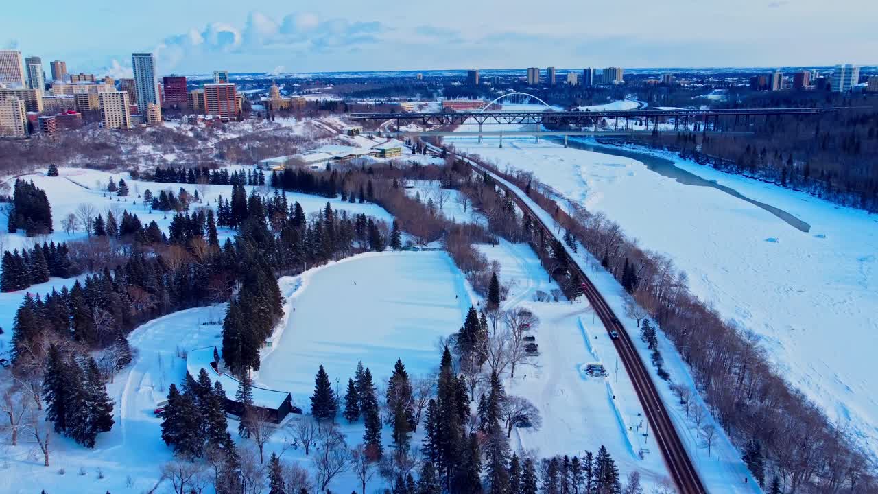 sobrevuelo aéreo invierno parque victoria hecho por el hombre pista de hielo tranquila conectada a una pista de patinaje infinito junto a la carretera forestal junto al río cubierto de nieve helado norte de saskatchewan borde de condominios centro de la ciudad 1-4