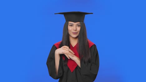 retrato de una estudiante confundida en disfraz de graduación diciendo oops, encogiéndose de hombros y mordiendo los labios. joven morena posando en el estudio con fondo de pantalla azul. primer plano. cámara lenta lista 59.94fps