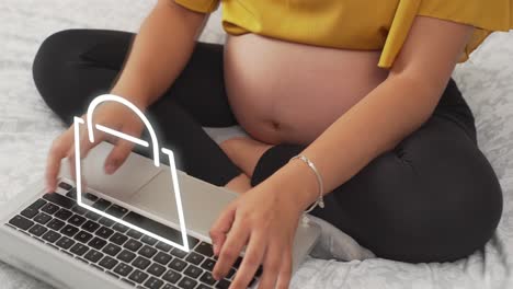 pregnant woman is shopping online with laptop and virtual shopping bag