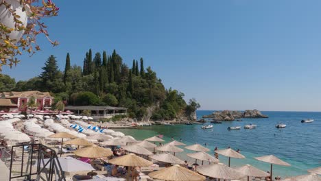 Toma-Panorámica-Que-Muestra-Las-Tumbonas-Y-Sombrillas-De-Playa-En-Parga,-Grecia