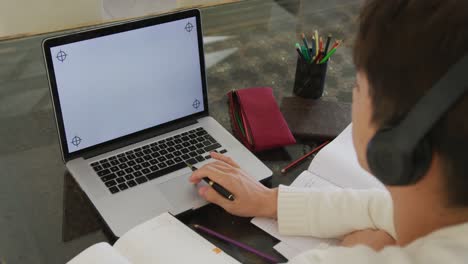 adolescente asiático con auriculares aprendiendo y usando computadora portátil en la sala de estar