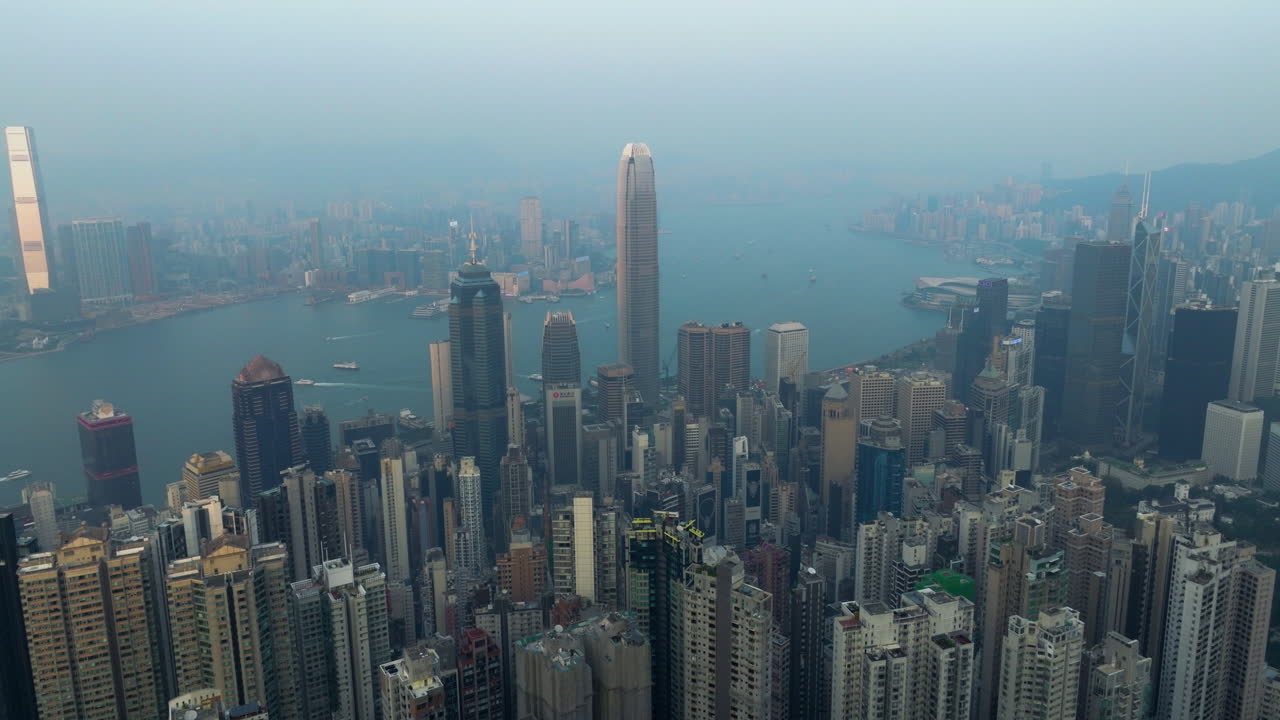 Množství mrakodrapů na ostrově Hong Kong a poloostrově Kowloon z Victoria Peak při západu slunce. Letecký záběr