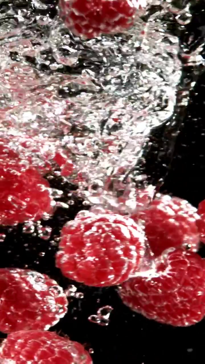Vibrant Red Raspberries Dropping into Water with Bubbles