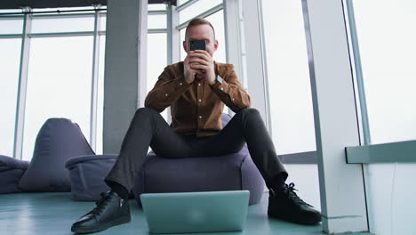 handsome businessman writing notes from smartphone at modern office