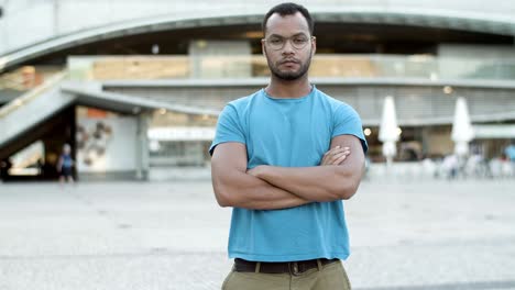 Confident-young-man-with-crossed-arms-standing-outdoors