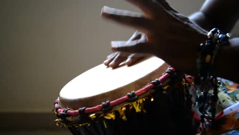 medium wide looking down isolated shot of a man playing djembe drum alone in a dark room