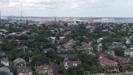 Aerial-pedastal-down-of-downtown-Charleston,-South-Carolina,-USA-with-cruise-ship-and-Ravenel-Bridge-in-the-background