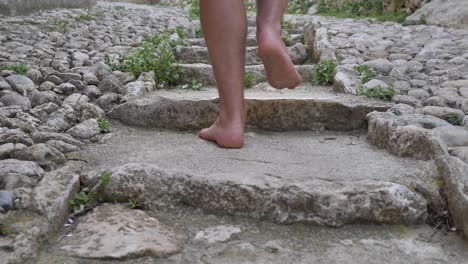 man with bare legs climbs up the old stone stairs close-up