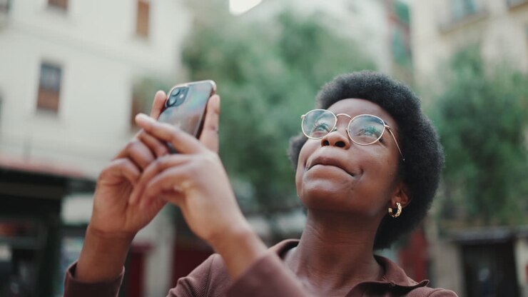 une jolie femme en lunettes avec un téléphone portable souriant dans la rue