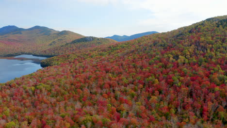 Slow-Aerial-Pan-of-a-Mountainous-Landscape-with-a-Lake-and-Vibrant-Red-and-Yellow-Leaves-Covering-the-Valley