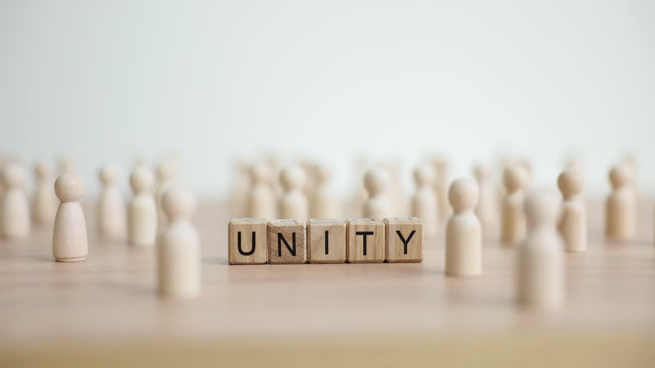 The word UNITY spelled out with wooden blocks surrounded by numerous wooden peg figures