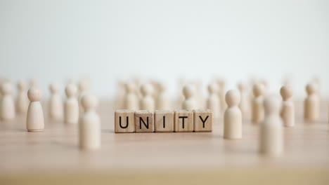 the word unity spelled out with wooden blocks surrounded by numerous wooden peg figures
