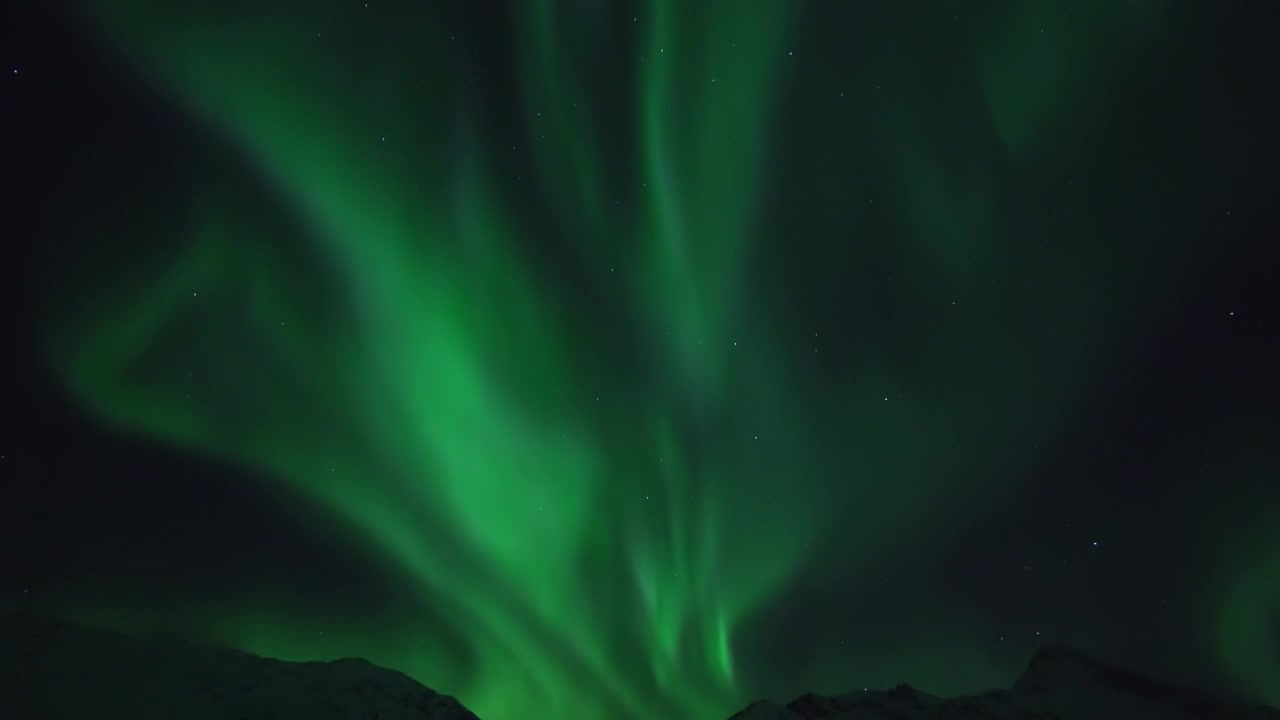 L'aurora boreale filmata in tempo reale su un paesaggio montano sull'isola Kvaløya vicino a Tromsø nella Norvegia settentrionale.