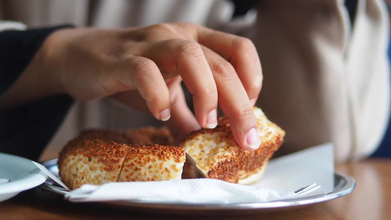 Person Eating Traditional Turkish Simit Bread in a Cafe
