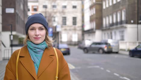 Happy-cheerful-positive-young-Caucasian-woman-walking-down-a-London-street-looking-around-and-smiling