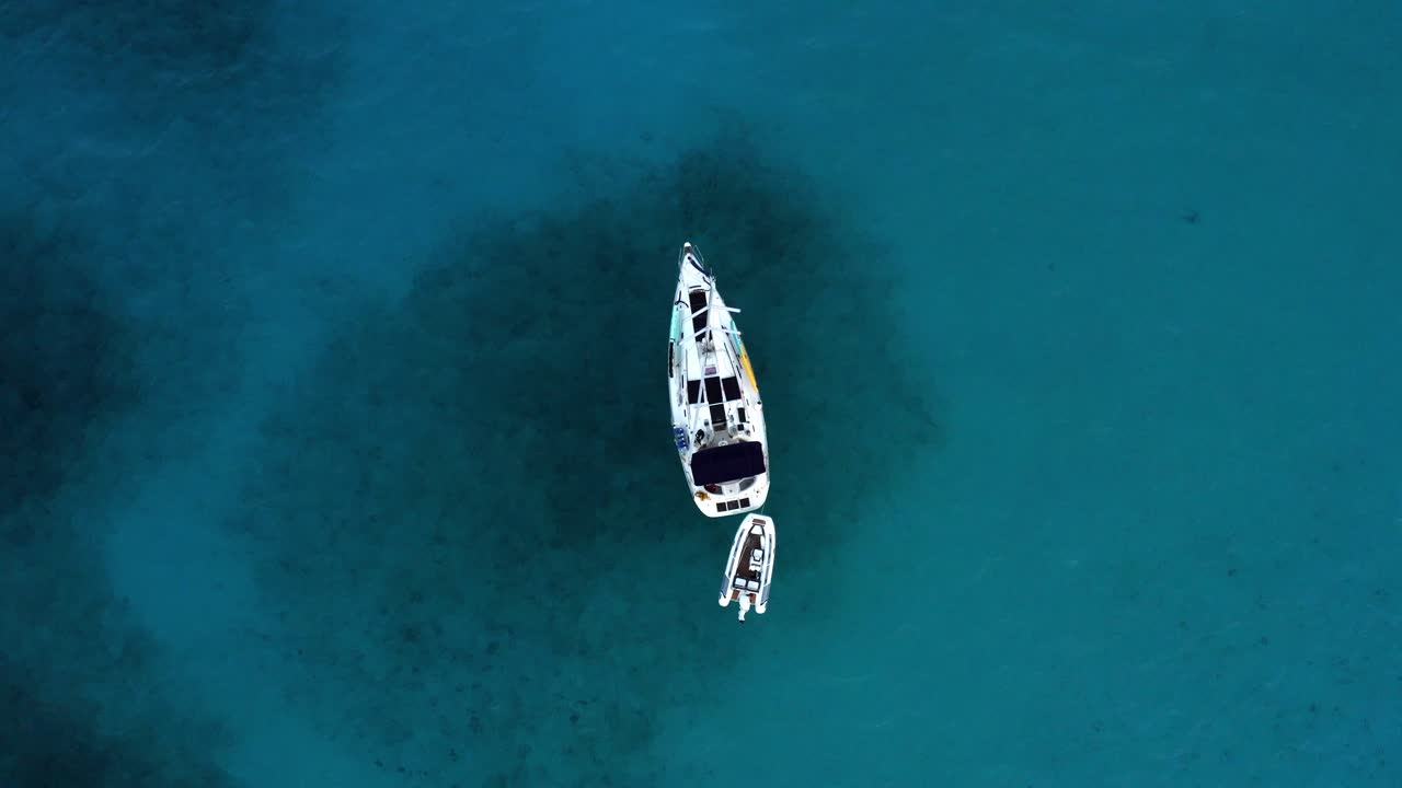 Barca a vela con gommone gonfiabile che galleggia su un mare blu cristallino vicino alle Bahamas nei Caraibi. - ripresa aerea