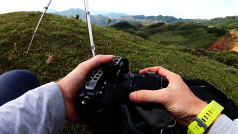 cambiando la lente de la cámara mientras estaba sentado en una colina, pov
