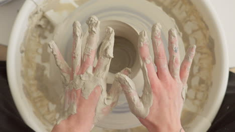 pottery artist cleans both his hands of sticky clay after finishing craft work