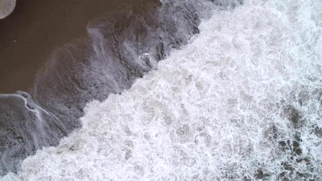 aerial view of the waves, sandy beach with reed umbrellas