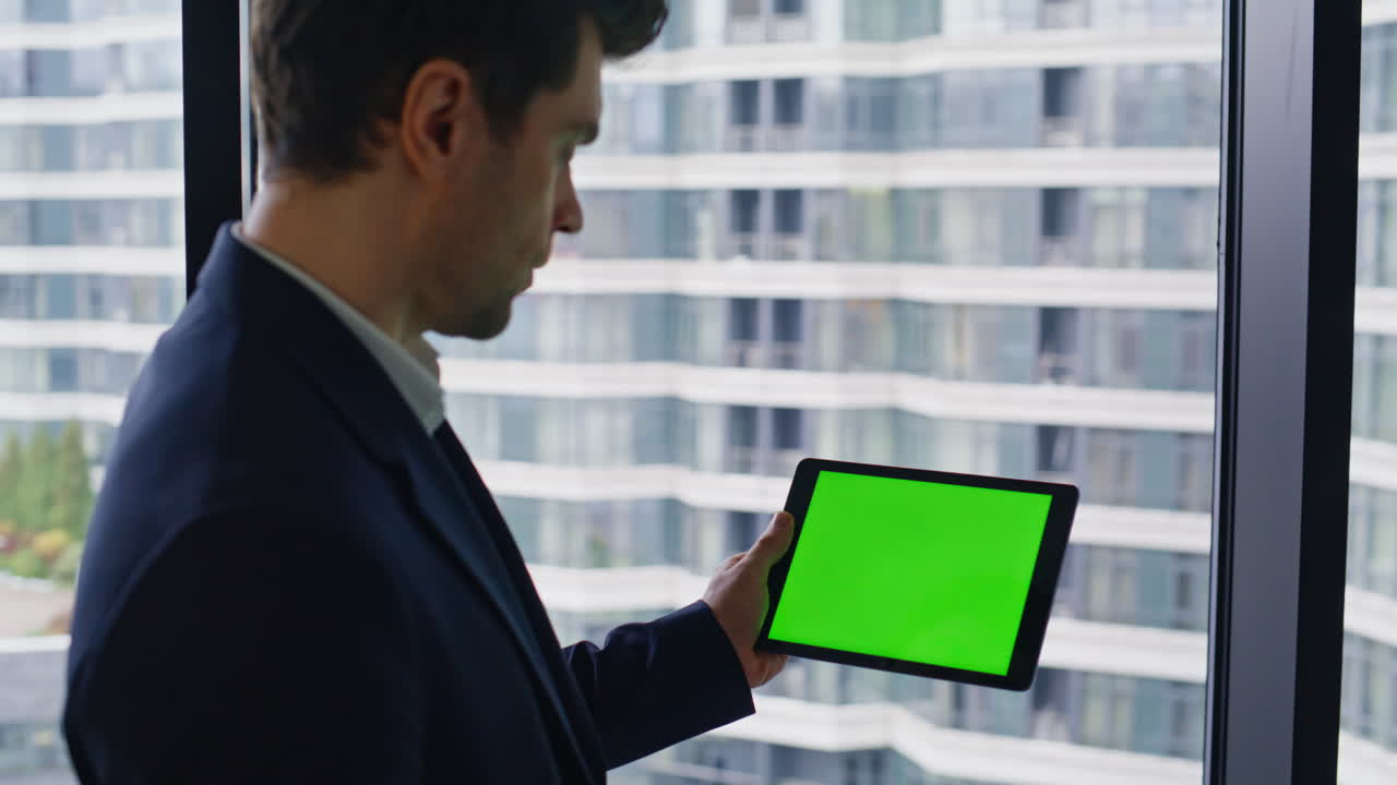 Man using tablet with green screen in front of window