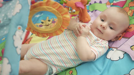 joyful baby lying on colorful mat