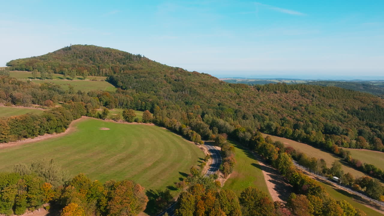독일의 가을 초기에 나무 벨트와 함께 산의 곡선 휘어지는 도로에서 자동차를 운전 - 항공 플라이오버