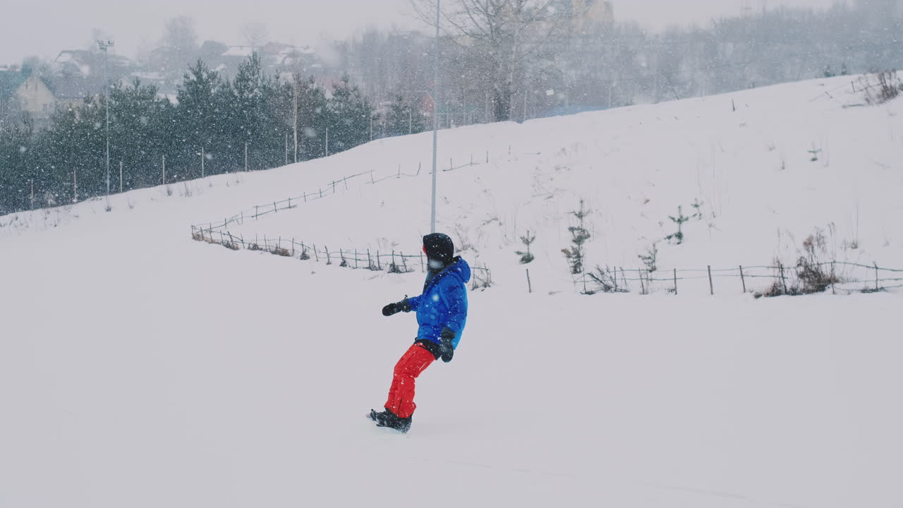 snowboarder masculino monta una tabla en la nieve desde la pista de esquí en cámara lenta