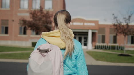 a child with a briefcase walks to a school building in the united states