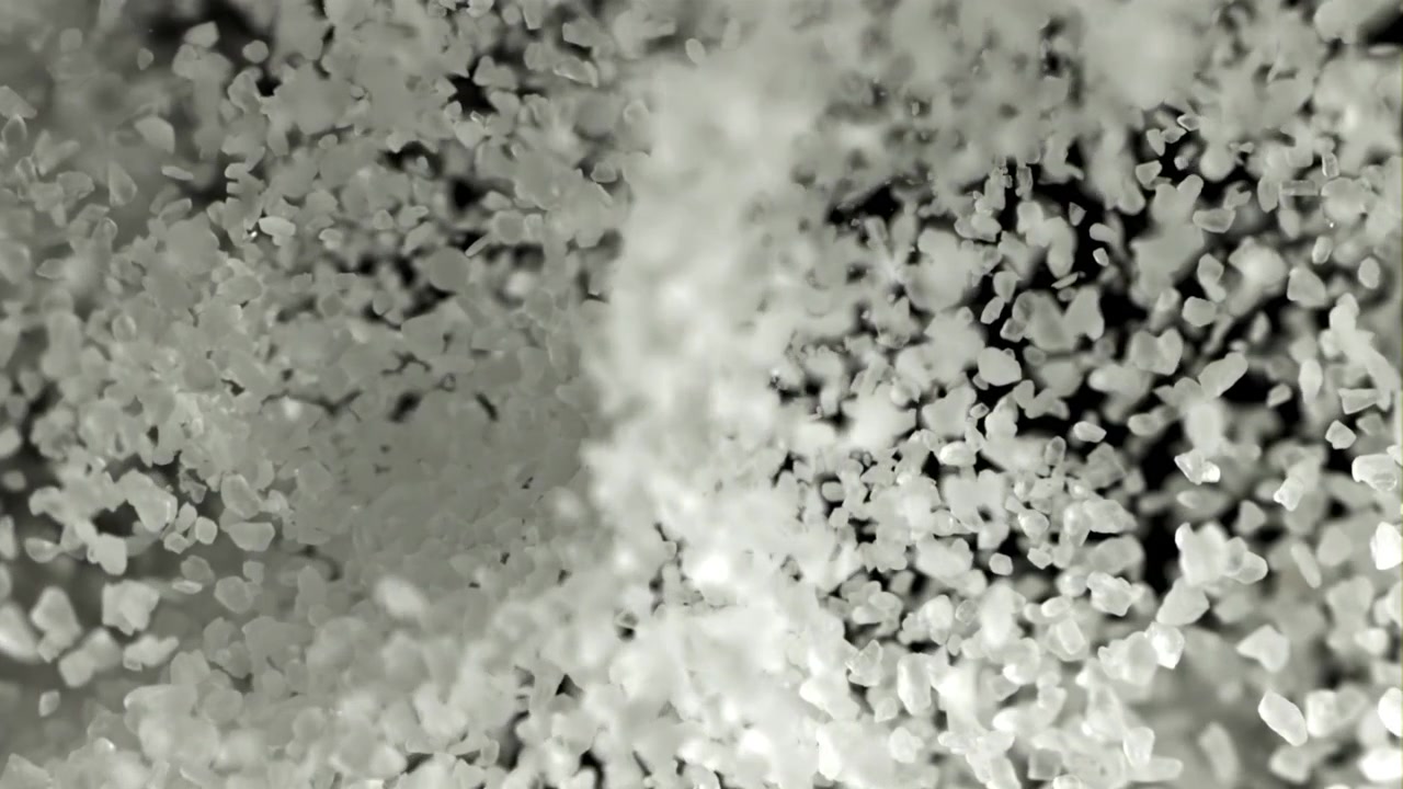 White Salt Crystals Falling in Slow Motion Against a Dark Background