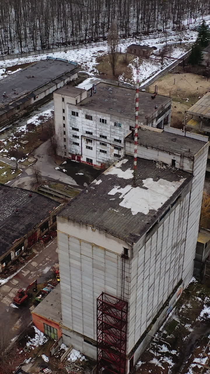Aged factory with ruined buildings. Abandoned industry in dark background after the war. Aerial view. Orbital shot. Vertical video