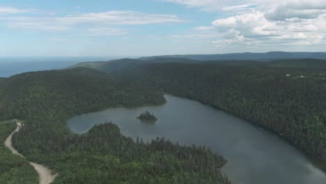 Lush-Forest-Surrounding-The-Calm-Lake-At-Saint-Anne-des-Mont-By-The-Gaspe-Peninsula-In-Summer-In-Quebec,-Canada