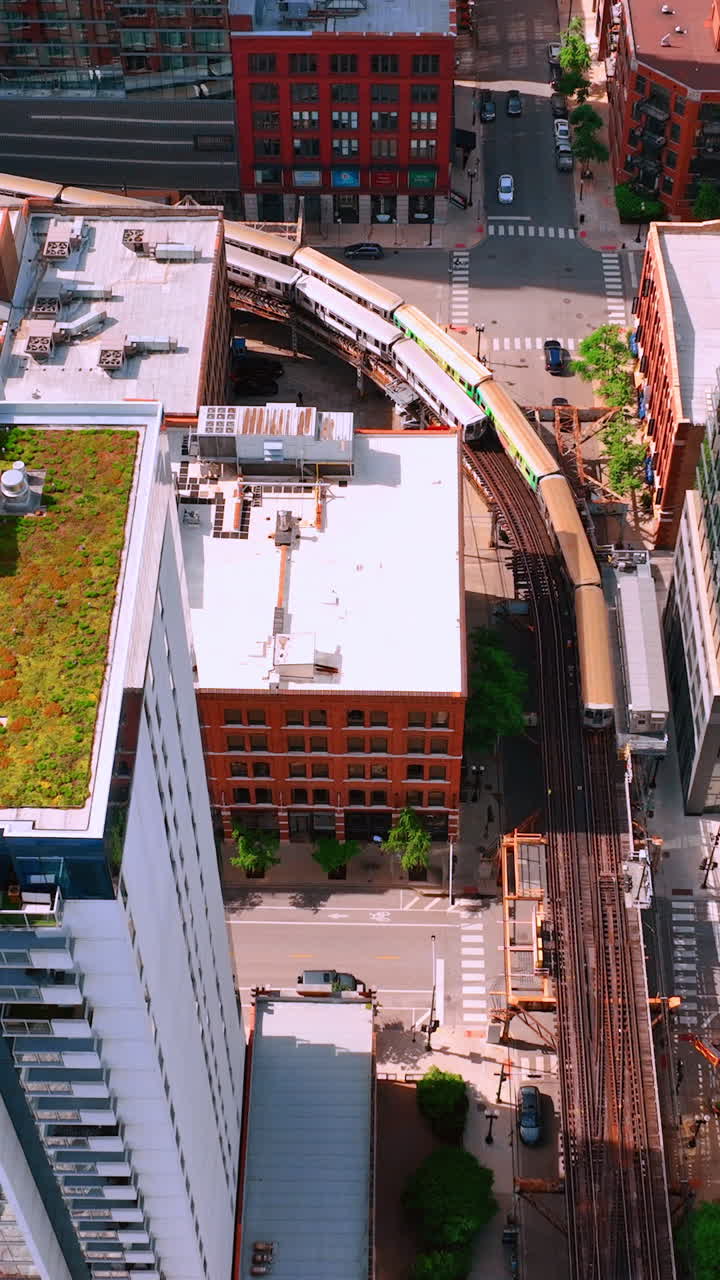 Chicago, Illinois, USA - June 01, 2024: Elevated train tracks are running above the railroad tracks between the building at the Loop line at Chicago. Aerial view. Vertical video