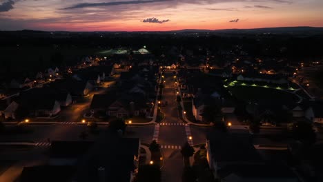 Seitliche-Drohnenaufnahme-Der-Beleuchtung-Von-Straßenlaternen-In-Einem-Amerikanischen-Viertel-Bei-Sonnenuntergang