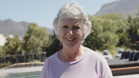 Portrait-of-smiling-senior-caucasian-woman-in-sunny-garden,-unaltered,-in-slow-motion