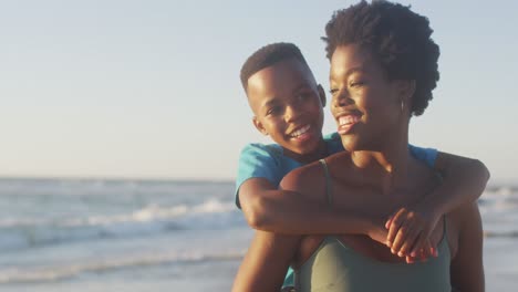 Video-Einer-Glücklichen-Afroamerikanischen-Mutter-Und-Ihres-Sohnes,-Die-Sich-Bei-Sonnenuntergang-Am-Strand-Amüsieren