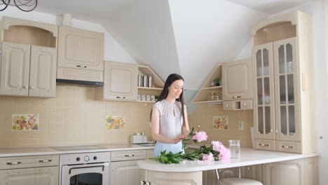 beautiful girl puts a bouquet of peonies in a vase in the kitchen beautiful girl puts a bouquet of peonies in a vase in the kitchen juicy comfort in the home kitchen