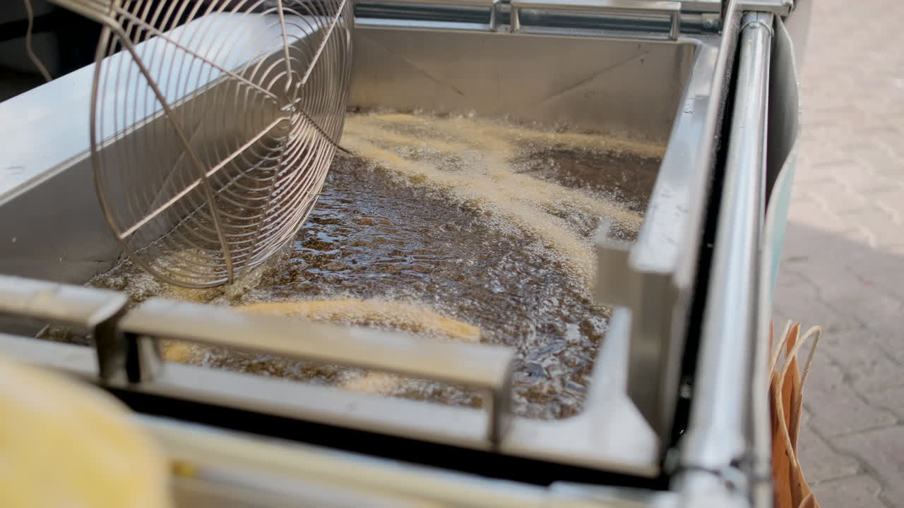 churros siendo fritos en una freidora profunda