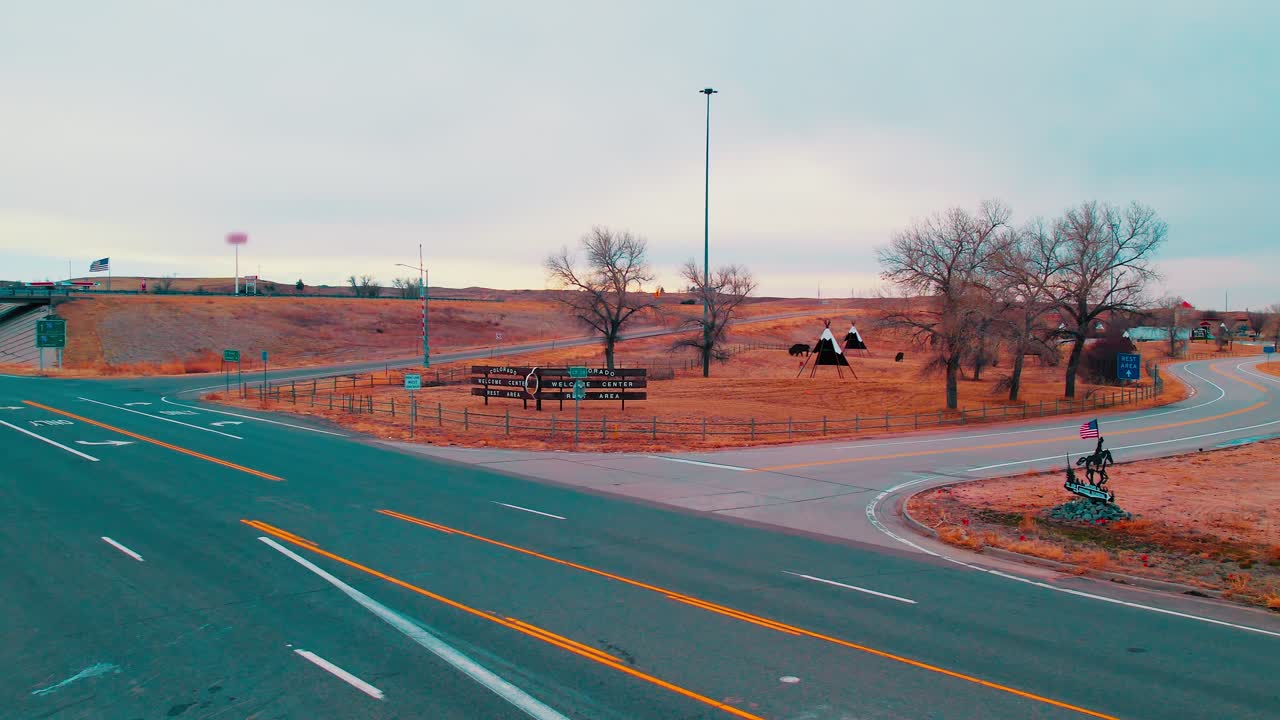 Colorado’s arid rest area entrance, featuring teepees, grazing bison, and open highways across dusty, wide-ranging plains.