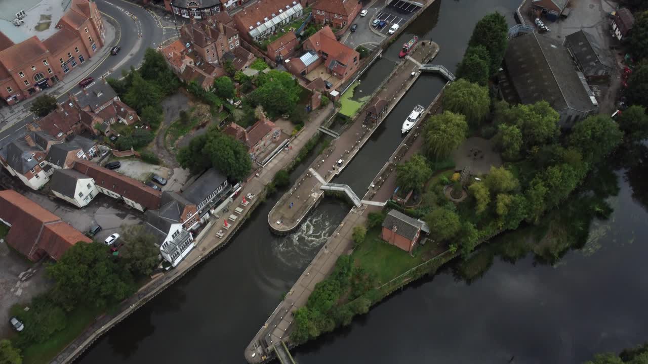 Drone video high over Newark Town Lock with a River Boat moored inside while the water level lowers. High and panned down as the footage moves across the lock and shows the surrounding buildings.