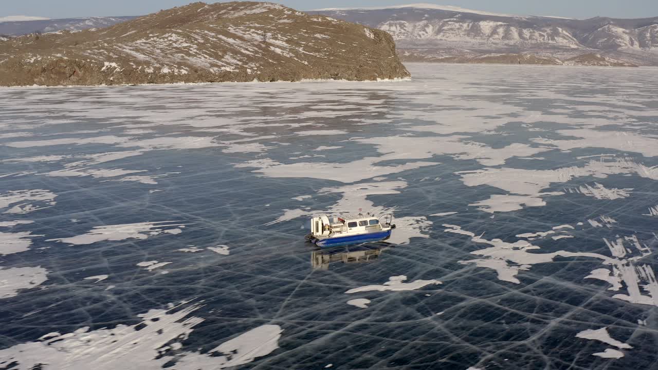 лодка с воздушной подушкой стремительно пересекает замерзшее озеро байкал.