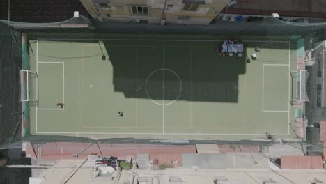 imágenes aéreas de niños jugando al fútbol en un campo rodeado de edificios en nápoles, italia