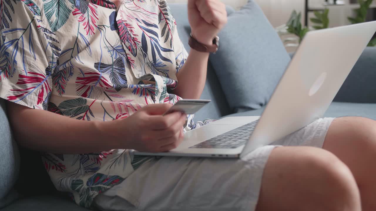 Cheerful Man Holding Credit Card And Using Smartphone Shopping Online In Living Room