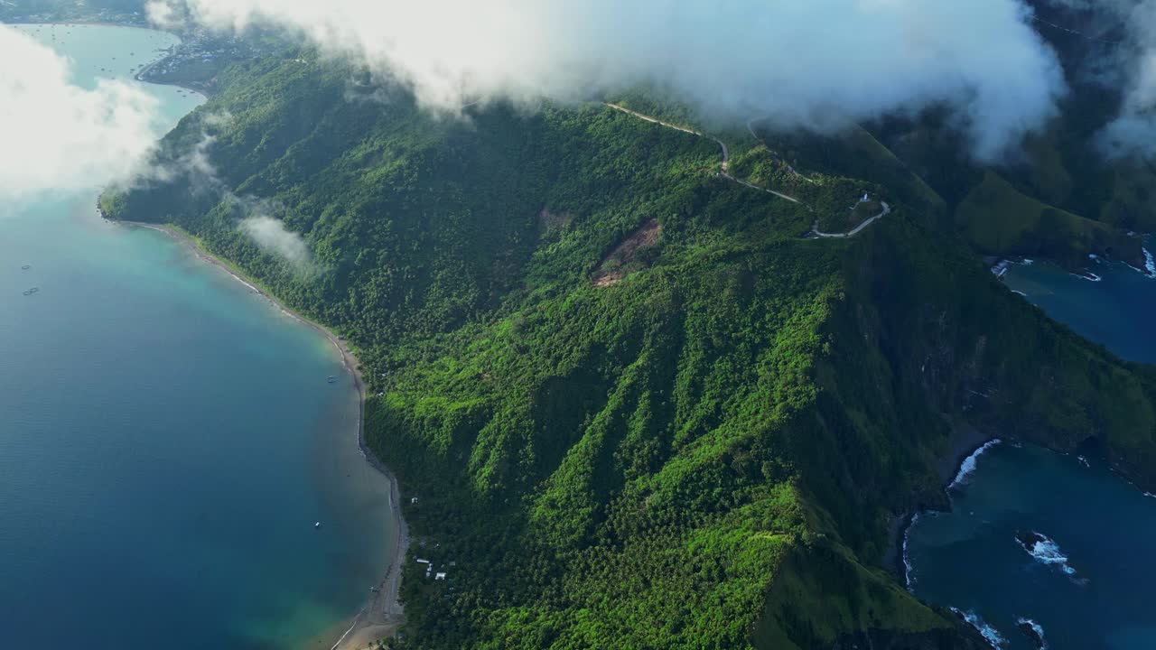 Slow upward tilt aerial in Dingalan, Aurora, rising sky‑high from the coastline and hills until clouds drift in, softly covering the distant ridges and horizon