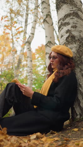 joven se sienta bajo un árbol en soledad, leyendo un libro pensativo en el bosque de otoño, rodeada de hojas doradas, abraza la calma, la inspiración y la creatividad en un tranquilo retiro al aire libre