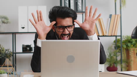 Office-businessman-hiding-behind-laptop-computer-making-funny-silly-face-fooling-around,-disrespect